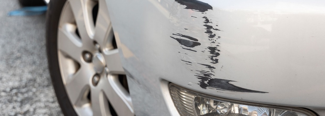 Een grijze auto met wat lichte schade op de voorbumper