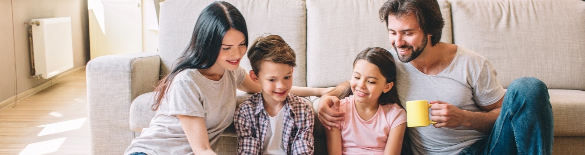 Familie, 2 ouders, 2 kinderen lezen samen in een boek 